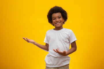 African American boy with black power hair on yellow background. Smiling black kid with a black...