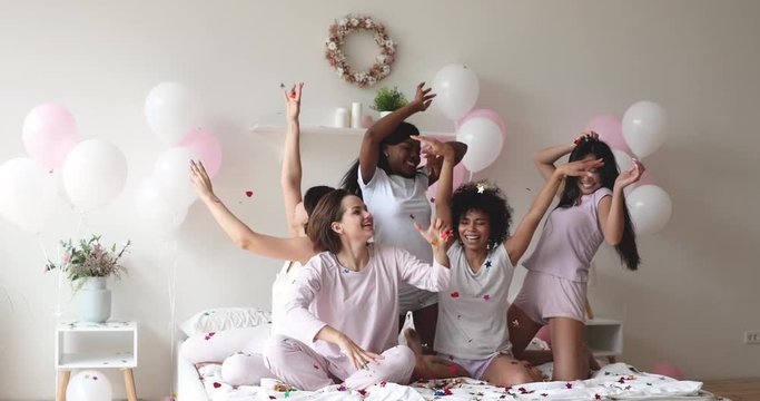 Carefree young diverse women celebrate pajama party throw confetti up