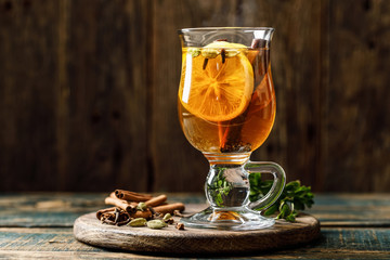 Grog. Hot drink for winter or autumn. Spicy tea and rum cocktail with lemon, cardamom, cinnamon and cloves. - obrazy, fototapety, plakaty
