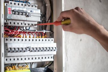 Man, an electrical technician working in a switchboard with fuses. Installation and connection of...