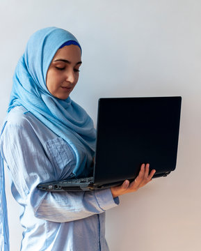 Young Arabian Muslim woman in hijab holding laptop pc computer