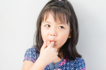 Tasty food and Delicious food concept.Portrait of funny lovely little asian girl put finger into mouth.Beautiful female child girl is showing delicious sign on white background.