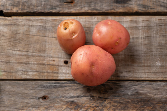 Pink cambray potato on wooden background
