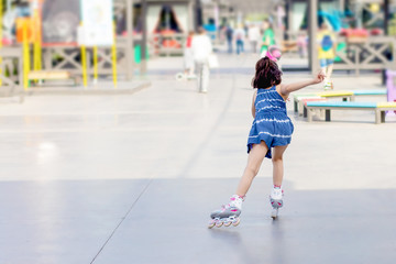little girl on roller skates in city park on summer sunny day