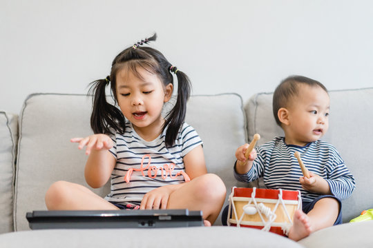 Little Sister And Her Baby Brother Play With Keyboard And Drum And Singing.Asian Child Playing And Singing Happy Moment In Music Time.Sibling Child Sing In Music Song Class At Home.