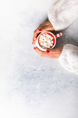 Female hands hold a cup of coffee with marshmallows . Holiday concept.