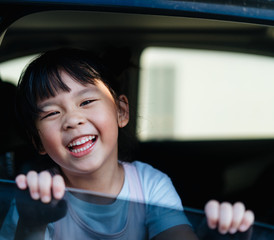 Transport, safety, childhood road trip and people concept - Happy little girl sitting in car, Child in auto car and laughing and smile.Happy Little asian girl child showing front teeth with big smile.