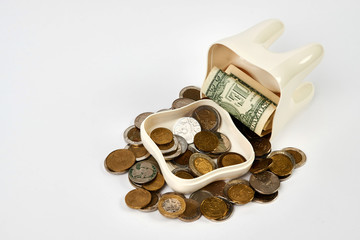 Tooth piggy bank with coins on white background with copy space