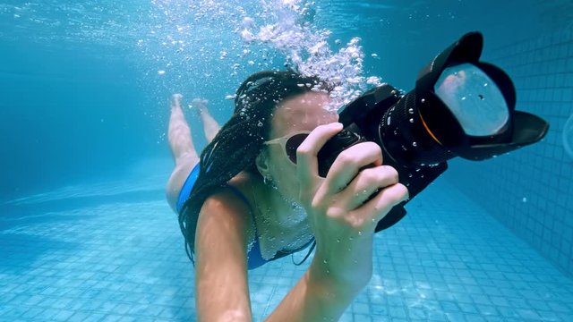 Young woman dives into the water. View from under the water, spray. Summer holiday concept, jump to the pool, Girl swimming underwater with camera.