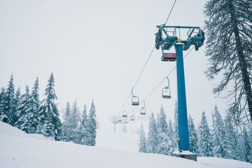 Ski lift with seats going over the mountain and paths from skies and snowboards.