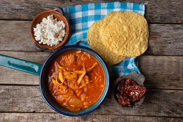 Mexican chicken tinga with chipotle pepper and fresh cheese on wooden background