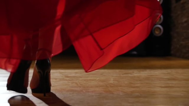 Female model in heels walking on hardwood floor in red dress
