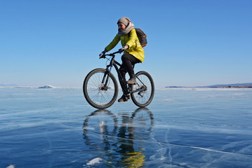 Ice biker traveler with backpacks on bike on ice of Lake Baikal. Winter sport concept. Cycling.