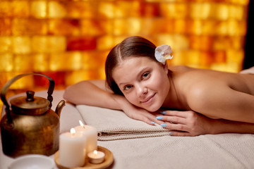 Obraz na płótnie Canvas Portrait of beautiful smiling woman lying on table after or before spa procedure, getting massage on back, look at camera and relax. Spa, health care, treatment concept