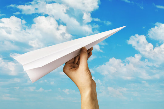 A man launches a paper plane into the sky. Hand with a toy airplane. Striving forward