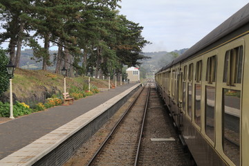 Fototapeta premium Station Platform, Rail Tracks and Train Coaches lines going off into diatance