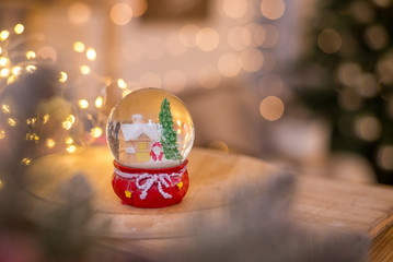 Christmas decoration, snow dome, globe with table decoration, Santaclaus on sleigh with child in winter scene, christmas tree with lights in background, selective focus