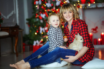 Mother with child in plaid shirts on the background of Christmas red candles and Christmas tree.