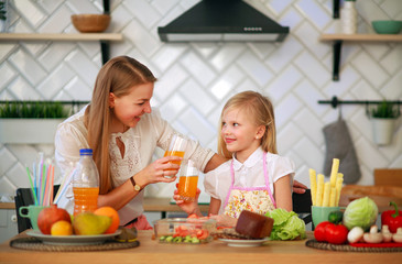 Family mother with daughter in kitchen drink orange juice, healthy lifestyle and nutrition