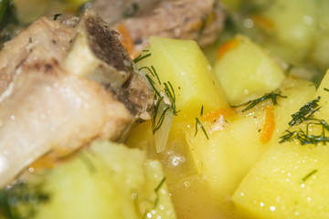 Stewed pork ribs with potatoes, onions, carrots and dill in a saucepan. Close up. Traditional recipe. Home cooking.