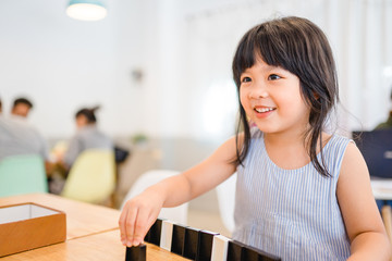 Bonding time! Father and his asian child girl are playing at home.Cute little asian girl play math game with her dad, sitting on the table at home office in Holiday.Family holiday and togetherness.