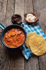 Mexican chicken tinga with chipotle pepper and fresh cheese on wooden background