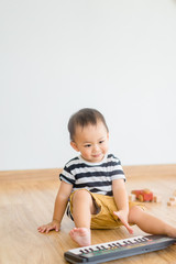 Naklejka premium Little baby boy play keyboard and drum at home.Asian boy playing and singing happy moment in music time.