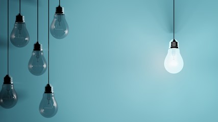 Hanging light bulbs on blue background with one illuminated and space for text