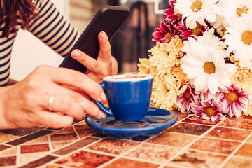 Pretty woman drinking coffee and using cellphone.	