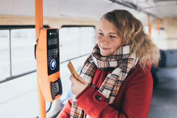 Young blonde woman making payment of public transport ticket fare at automatic contactless machine...