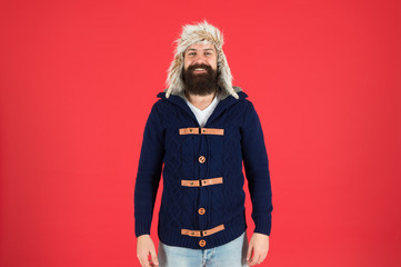 Fashion menswear shop. Masculine clothes concept. Winter menswear. Clothes design. Man bearded stand warm jumper and hat on red background. Winter season menswear. Hipster rustic style furry hat