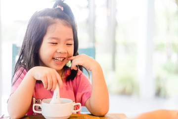 5 years old asian girl eating hong kong congee or rice porridge on breakfast time.Happy time in breakfast with asian food everyday.