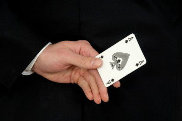 close up of a hand behind the back holding an ace of spades