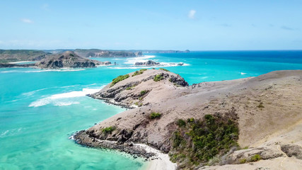 Waves splashing on a headland around Tanjung Aan beach. Dangerous phenomenon on a heavenly beach. Water is bubbled from the strength of the crushing waves. Beauty of the nature.