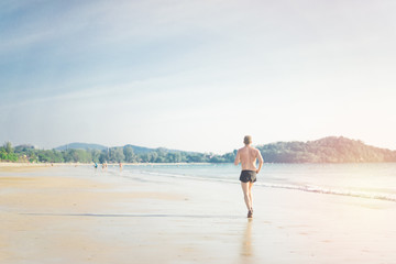 Man running on the beach in Sunset time.Summer paradise beach of Phuket island.Cardio, runner, running in Marathon concept.