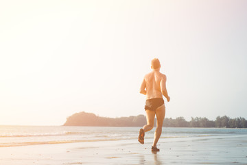 Man running on the beach in Sunset time.Summer paradise beach of Phuket island.Cardio, runner, running in Marathon concept.