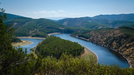Obraz na płótnie Canvas Meander of Melero with mountains around and a blue sky, Riomalo de Abajo (Cáceres), Spain