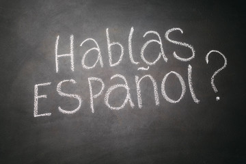 Spanish language learning concept. Inscription HABLA ESPANOL on blackboard.