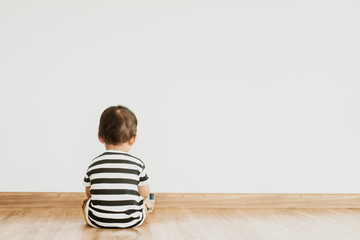 Back view of Little baby boy sitting alone and watching smartphone.