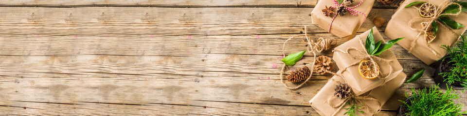 Zero waste christmas concept. Stack of handmade christmas gift boxes in craft paper with  different organic decoration and little live xmas tree in flowerpots.