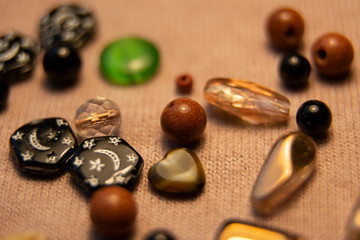 Beads of various shapes and colors on a pink woolen background.