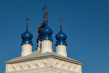 Fototapeta na wymiar Blue and gold domes of an old Orthodox church against a blue cloudless sky