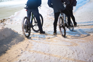 Cyclists in winter on the streets of the city ride on a snowy road.
