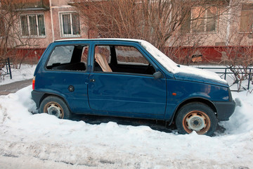 a car parked near the house seen by snow with broken windows in winter