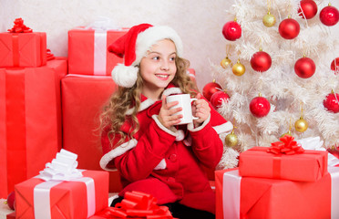 Obraz na płótnie Canvas Girl little cute child hold mug with hot drink while celebrate christmas. Hot cocoa on christmas eve. Cocoa favorite drink. Kid santa hat enjoy cocoa beverage . Perfect way to warm you holiday season