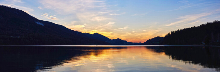 Lone fisherman catches fish on the lake Fuschl.  Austrian Alps, Salzburg region. 