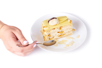 coconut cake with peach on a porcelain plate on the white background, tea spoon and female hand. Close-up served. Isolated on white background.