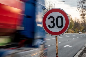 A fast driving blue speeding truck with motion blur effect near the traffic sign limiting the...