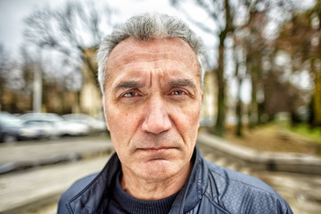 Middle-aged man with a serious look on the street. - Powered by Adobe