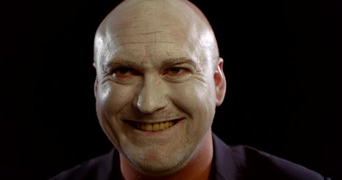 bald guy plays strange character looking aside and laughing